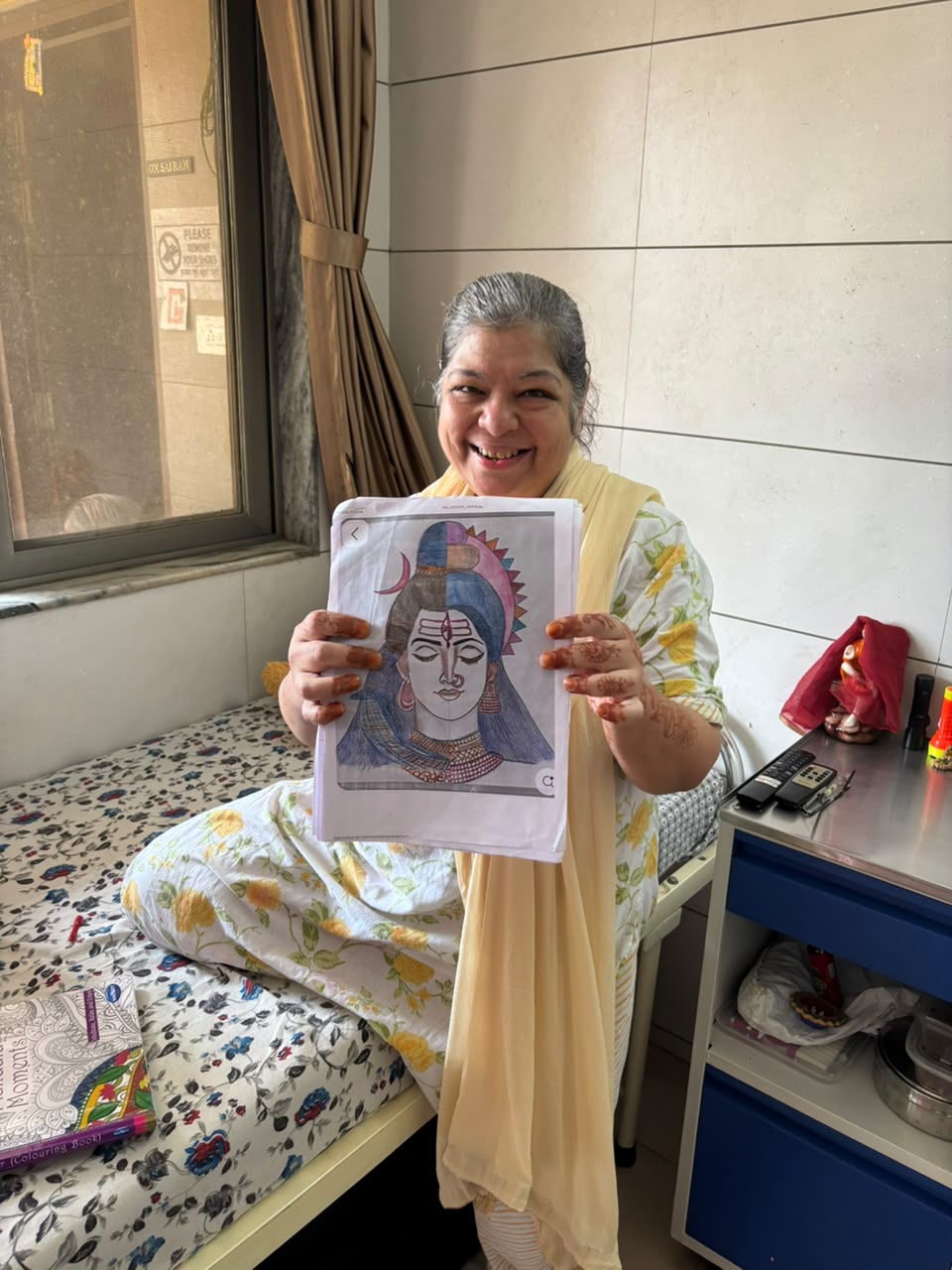 A resident smiling and holding up a devotional colouring-book picture she completed
