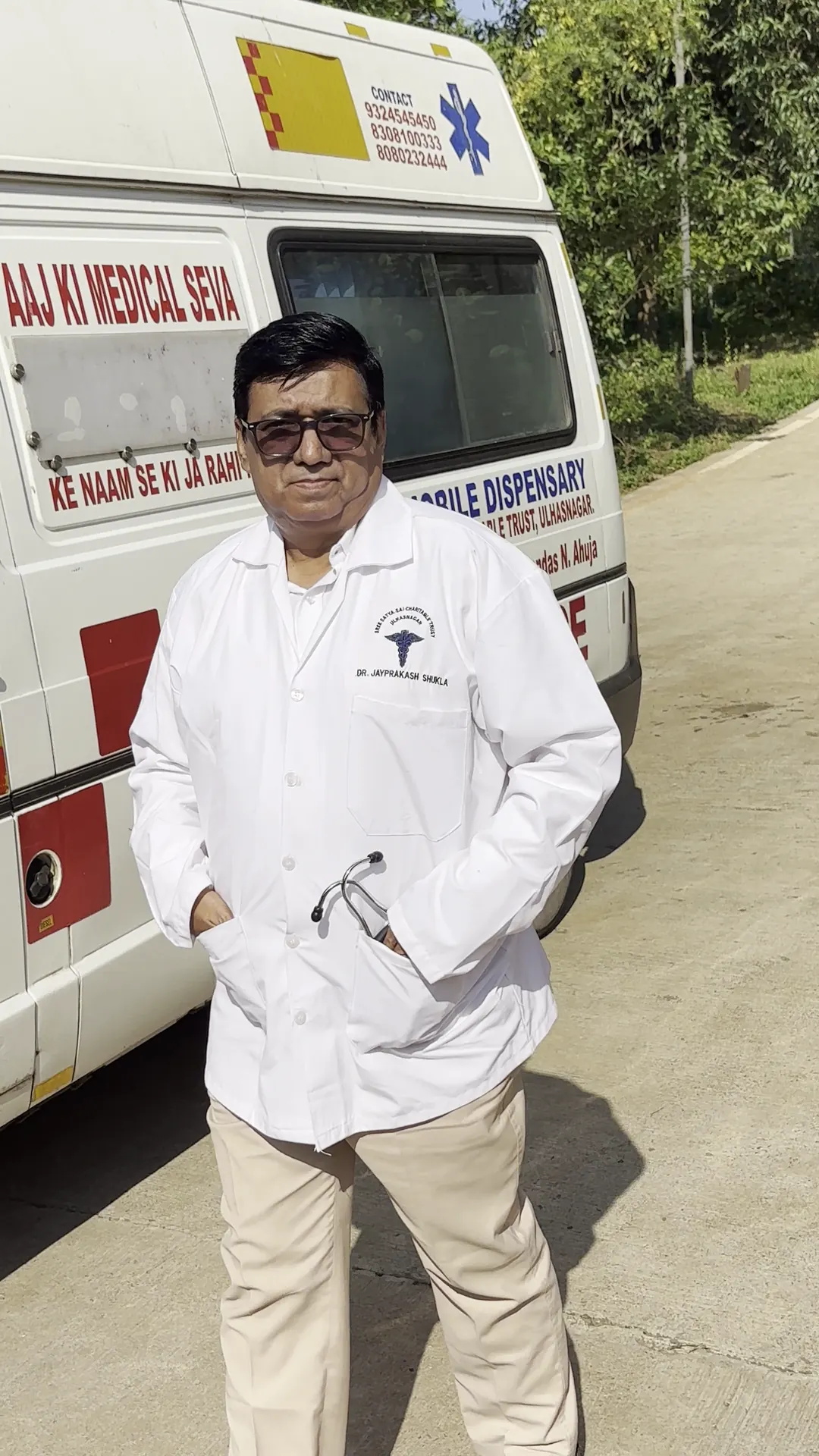 A doctor in a white coat standing beside a vehicle marked as a mobile medical dispensary